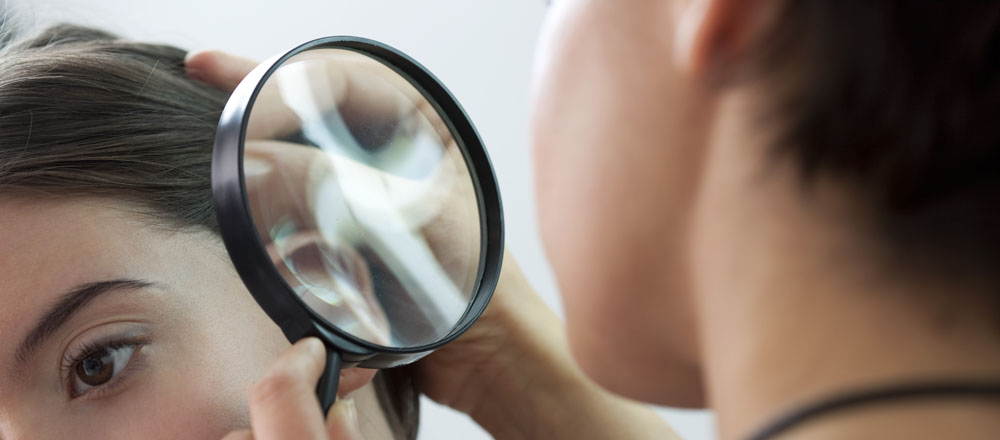 A dermatologist inspecting a patient's scalp